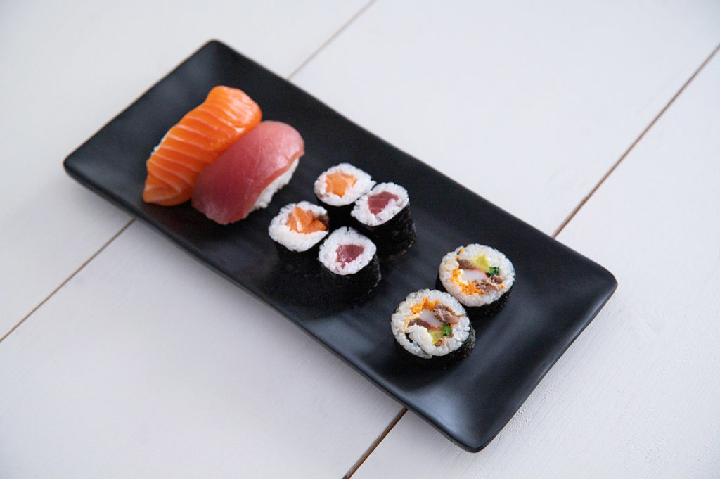 Nigiri Sushi neben Makirollen und Kimbaprollen.