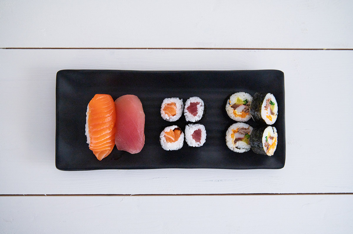 Je zwei Nigiri Sushi, vier Makirollen und vier Kimbaprollen nebeneinander zum Vergleich.
