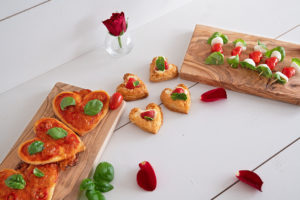 3 verschiedene Valentinstagssnacks: Minipizzen in Herzfor, Blätterteigherzen und Tomaten-Mozzarella-Spieße in Herzfor.